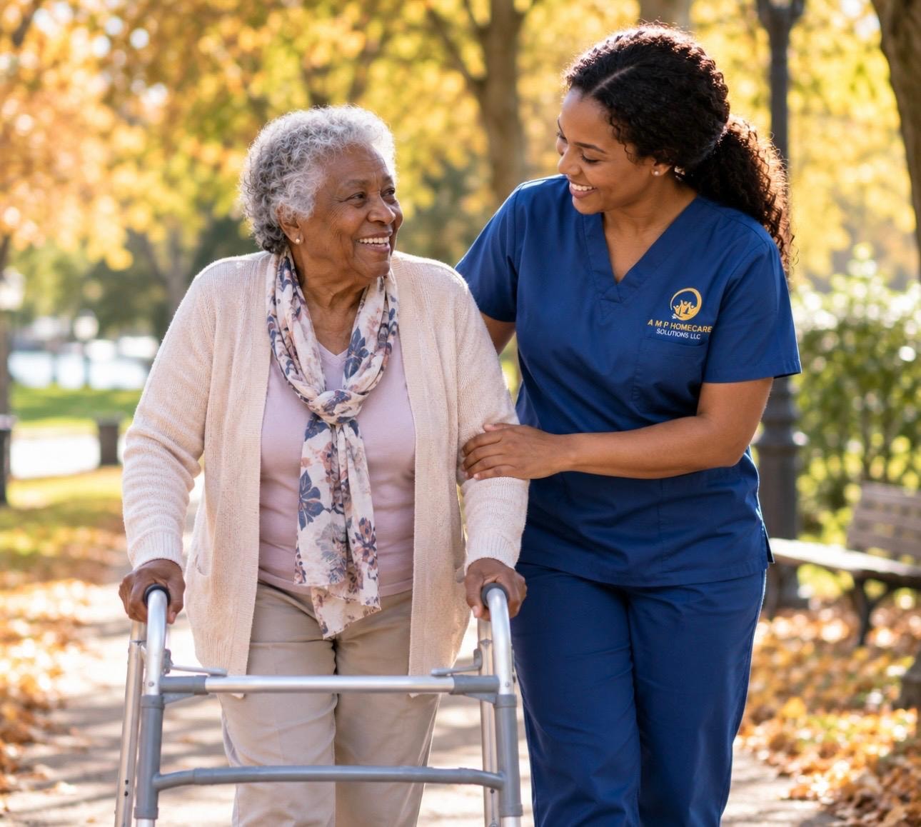 AMP HomeCare Solutions caregiver in branded navy scrubs walking outdoors with an elderly client using a walker — consistent, compassionate long-term care